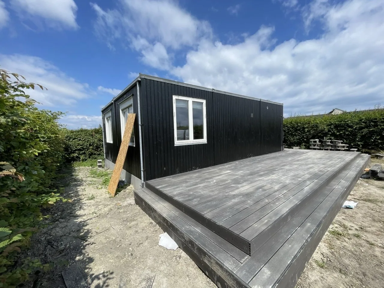Anneks med sort træbeklædning og ny terrasse