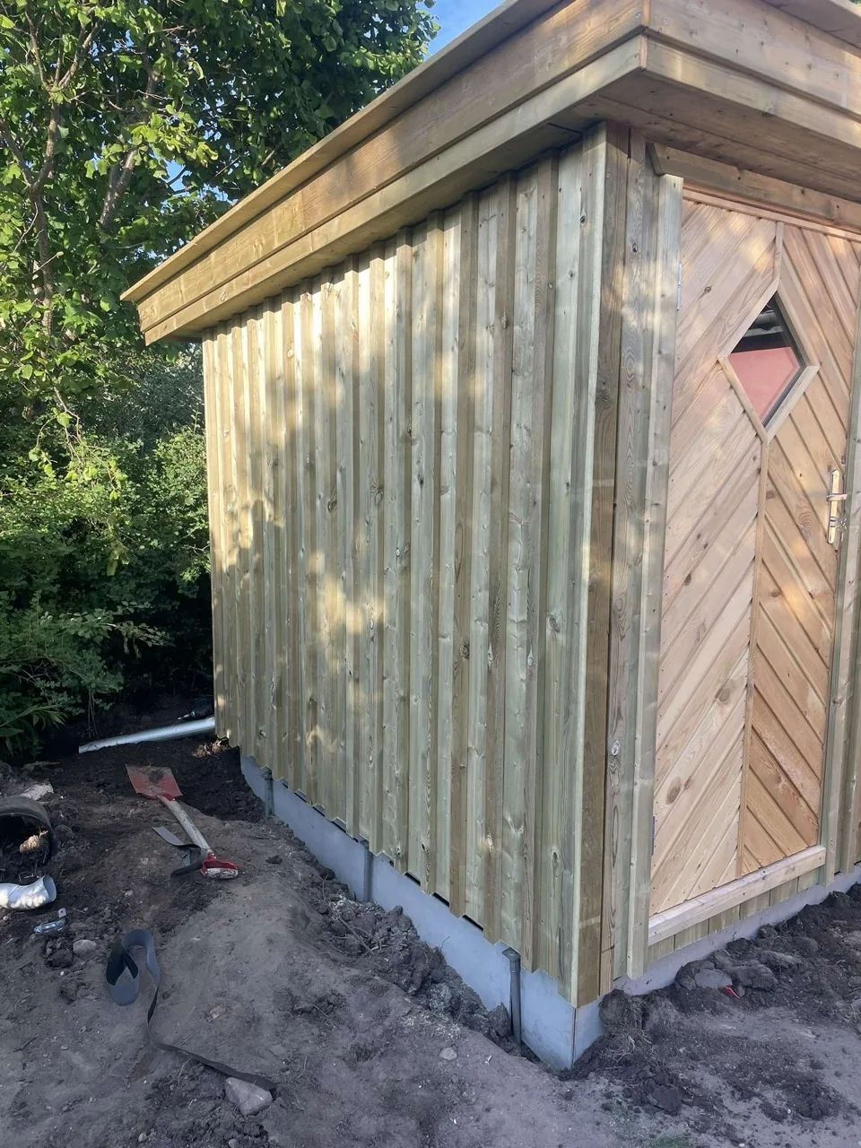 Skur med lodret beklædning af brædder på et støbt fundament